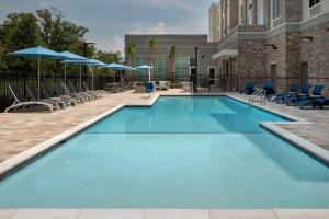 彭萨科拉Hilton Garden Inn Pensacola Downtown的游泳池,酒店配有椅子和遮阳伞