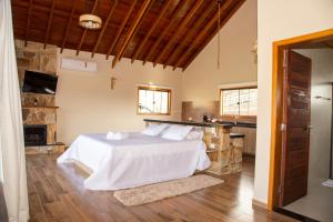 圣本图-杜萨普卡伊Chalé Pedra Madeira的一间带白色床的卧室和一间厨房