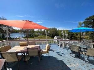 Long PondStunning Lakefront Home - Swim, Fish, Kayak, HotTub的露台配有桌子和遮阳伞。