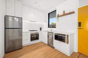 瑟尔Peppertree Apartments的厨房配有白色橱柜和不锈钢冰箱