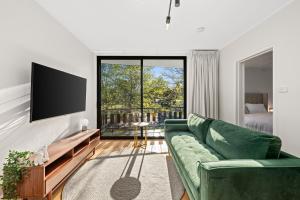 瑟尔Peppertree Apartments的客厅配有绿色沙发和平面电视