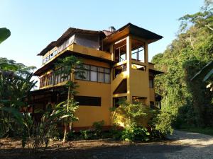 PillcopataParaiso Pilcopata Inn的一座种有树木的山丘上的黄色房子