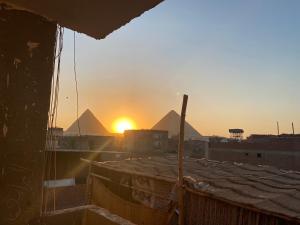 开罗Zein Pyramids View - Guest House的从大楼欣赏日落金字塔的景色