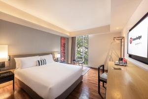 曼谷Travelodge Sukhumvit 11的卧室配有一张白色大床和一台平面电视。