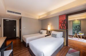 曼谷Travelodge Sukhumvit 11的酒店客房设有两张床和一张桌子。