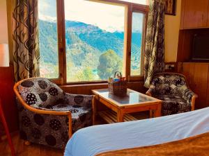 马拉里Shree Ram Cottage, Manali ! 1,2,3 Bedroom Luxury Cottages Available的客房设有床、桌子和窗户。