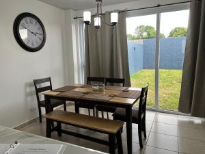 松索纳特Comfortable and roomy, in Sonsonate的餐桌、椅子和墙上的时钟