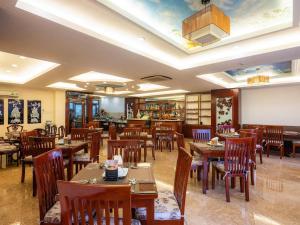 胡志明市Bon Ami Hotel - Thiên Xuân Hotel的餐厅设有木桌、椅子和天花板