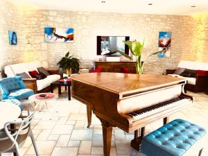 阿瓦耶Le Pigeonnier du Perron Hôtel的客厅配有钢琴和沙发
