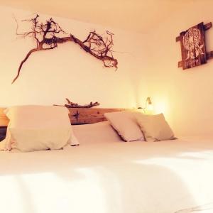 SoultzerenLodge bien être et nature的卧室配有一张带白色床单的床,墙上有一条支架