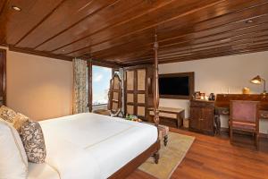 达兰萨拉Brij Anayra Dharamshala - A Himalayan Luxury Retreat的一间卧室配有一张床、一张书桌和一台电视