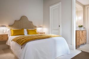 塞维利亚Magno Apartments Casa Pilatos的白色卧室配有一张带黄色枕头的大床