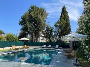 戛纳Villa Alexandra Luxury Apartments by Sweet Inn的一个带椅子和遮阳伞的游泳池