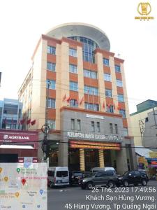 广义洪王酒店的一座大型建筑,前面有汽车停放
