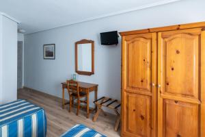 桑坦德圣格洛里奥酒店的一间卧室配有木制橱柜和一张书桌