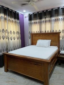 巴加莫约Bagamoyo Home Stay的配有窗帘的客房内一张大型木床