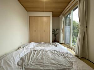 Shimoda南あその丘的卧室内的一张白色床,设有窗户