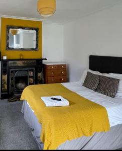 诺里奇Golden Triangle Rooms的一间卧室配有一张带黄毯的床和壁炉