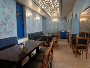 阿格拉玛雅酒店及餐厅的餐厅设有桌椅和蓝色的墙壁