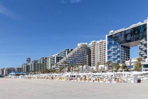 迪拜Super Spacious 3BR with Maid's Room in Five Palm的海滩上设有椅子和遮阳伞,还有建筑