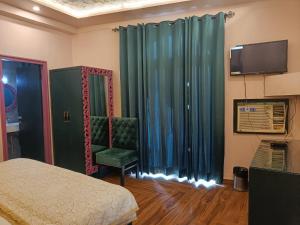 阿格拉玛雅酒店及餐厅的一间卧室配有一张床、一把椅子和电视