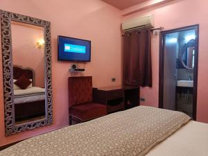 阿格拉玛雅酒店及餐厅的一间卧室配有一张床、镜子和椅子