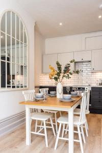 索尔兹伯里3 Castle Mews的白色的厨房配有木桌和椅子