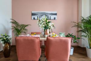 弗罗茨瓦夫地区别拉内Hotel A4 Wrocław - Bielany - MAMY WOLNE POKOJE !的餐桌,配有粉红色的椅子和植物