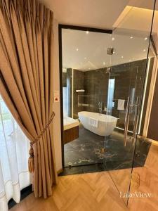 海岸角Executive Suite Apartment in Cape Coast - Lakeview by Agnes的带浴缸和大型玻璃淋浴间的浴室。