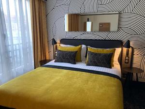 巴黎莫迪利亚尼别墅蓝色假日酒店的一间卧室配有一张黄色的床和条纹墙
