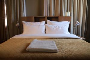 贝鲁特Hotel Lost的一张带白色毯子和毛巾的床