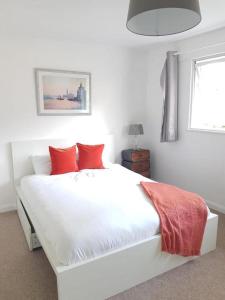 斯坦福勒霍普Lovely 2-Bed Apartment in Stanford-le-Hope的卧室内的白色床和红色枕头