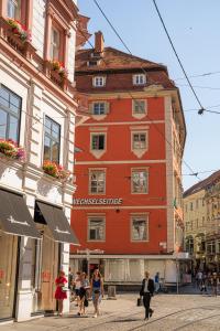 格拉茨Kaiser Apartments - City Centre of Graz的一座红色的建筑,人们在街上行走
