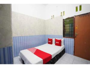 泗水OYO Life 93061 Kost Vicky Syariah的一间卧室配有一张带两个红色枕头的床