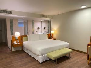 乌鲁班巴阿让洼圣谷疗养酒店的卧室配有一张白色大床和绿色凳子