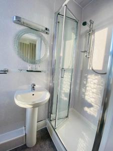 兰迪德诺Cwtch Guesthouse的浴室配有盥洗盆和带镜子的淋浴