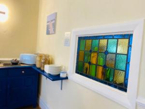 兰迪德诺Cwtch Guesthouse的厨房的墙上设有彩色玻璃窗