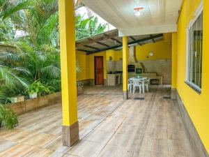 安格拉杜斯雷斯Casa com churrasqueira e piscina, perto de riacho的黄色的房子,设有配有桌子的庭院
