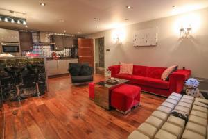 伦敦The London Nest: 2BR City Haven的一间带红色沙发的客厅和一间厨房