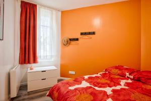 勒阿弗尔Le Havre - Quartier des Docks au Calme - 4 Appartements Entièrement Rénovés - NOUVEAU的一间卧室设有橙色的墙壁和一张带花毯的床