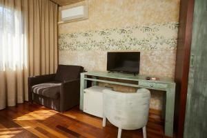 坎德莱达Hotel El Mirlo Blanco的客厅配有书桌、电视和椅子