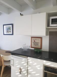 格鲁瓦BRISE MARINE的厨房配有白色橱柜和黑色台面