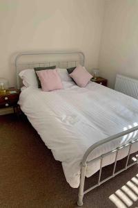 兰鲁斯特Cosy Cottage, Nr Betws y Coed.的床上配有粉色和白色枕头的床
