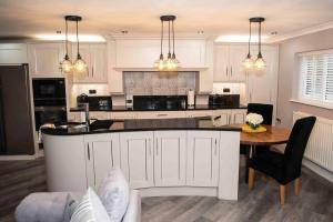WoodhouseLittle Retreat的厨房配有白色橱柜、桌子和柜台。