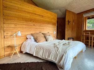 富塔莱乌富Peuma Lodge Patagonia的一间卧室设有一张带木墙的大床