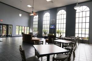 弗林特Baymont by Wyndham Flint Airport North的餐厅设有桌椅和窗户。