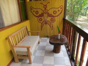 PillcopataParaiso Pilcopata Inn的阳台的门廊配有长凳和桌子