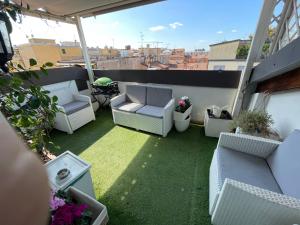 博洛尼亚Suite Indipendenza 58的阳台的天井配有白色椅子和草地。