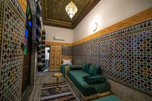 非斯Riad Qamar Fez的客房设有绿色沙发和瓷砖墙