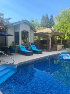 Cameron ParkTuscany Dorado Resort的一个带蓝色椅子的游泳池和一个凉亭